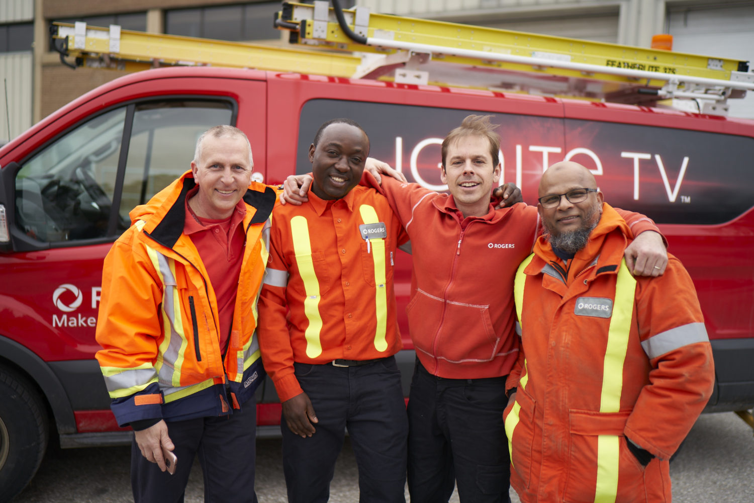 Four Rogers technicians standing in front of a Rogers van