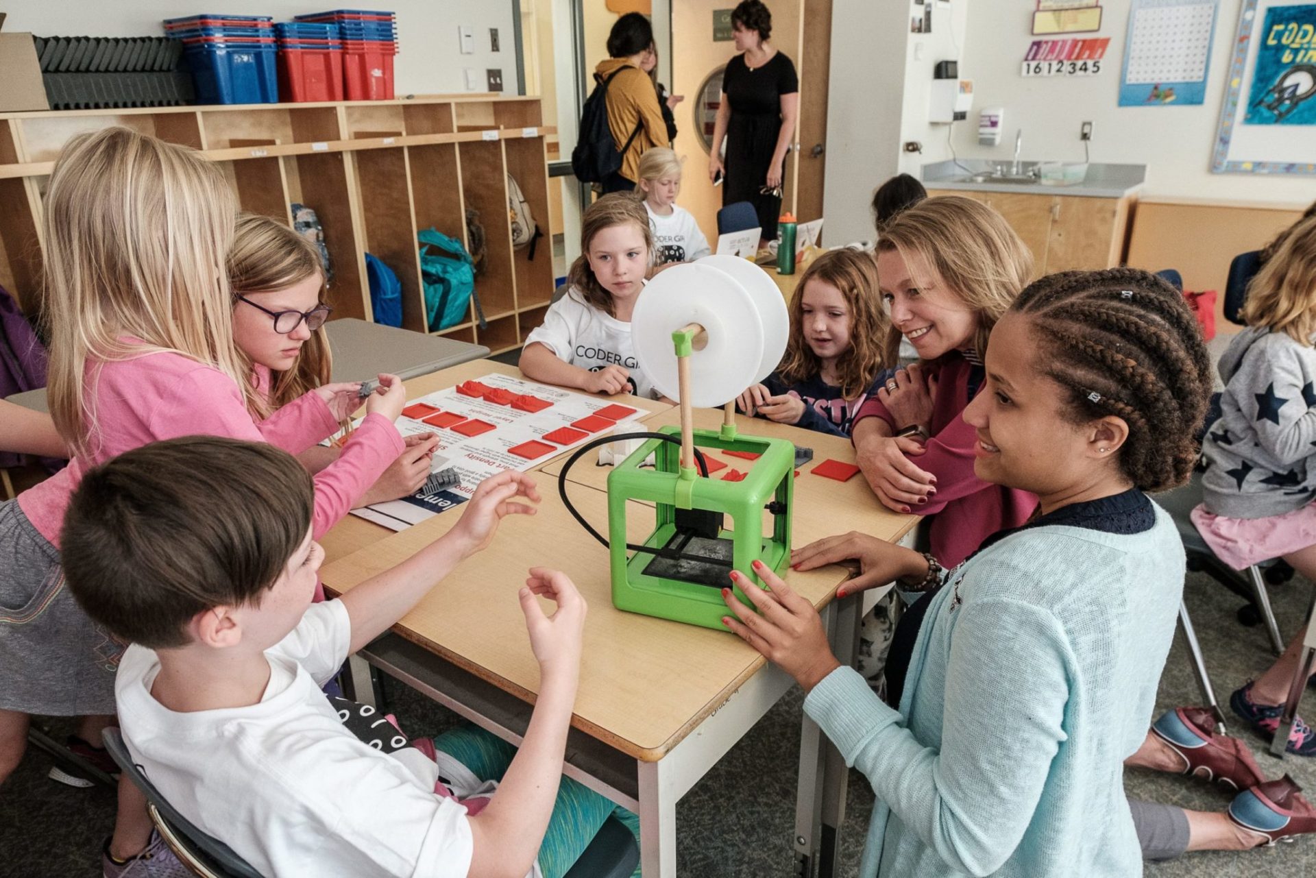 Group of children and teacher at desk inside classroom doing a project