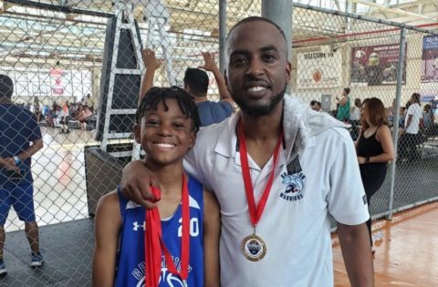 Rogers employee Terone Harris with child in gym wearing medals from sporting competition