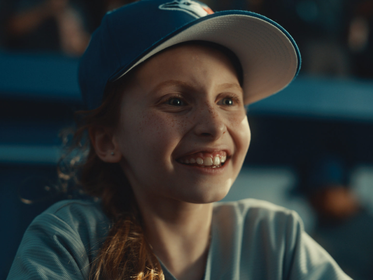 Happy child wearing Toronto Blue Jays hat at baseball game