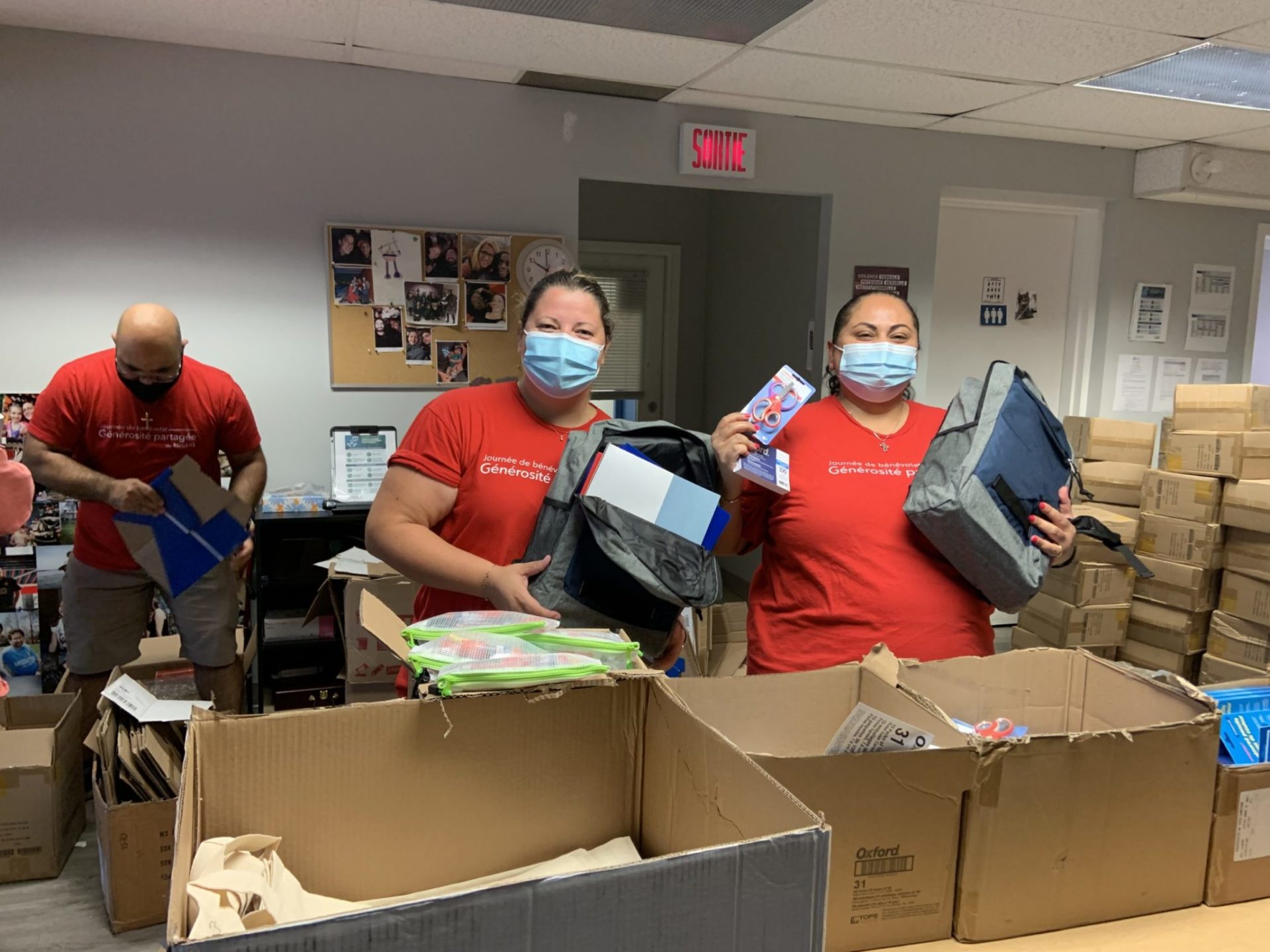 Rogers volunteers packing school supplies in boxes inside office